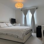 Modern bedroom with bed, desk, and soft lighting