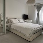 Bright bedroom with double bed and white decor.