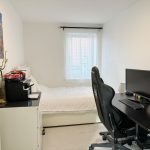 Modern bedroom with desk and computer setup.
