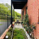 Charming garden path beside brick house with plants.