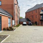Modern red brick apartment building with parking area.