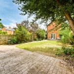 Sunny garden with lawn and paved patio.