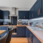 Modern kitchen with navy cabinets and wooden worktops.