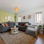 Modern living room with grey sofa and playpen.
