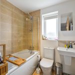 Modern bathroom with bathtub, sink, and toiletries.