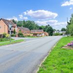Quiet suburban street with houses and greenery.