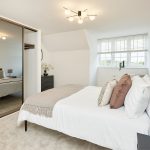 Modern bedroom with double bed and mirrored wardrobe.