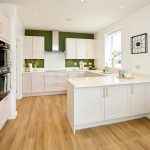 Modern kitchen with white cabinets and wooden floor.