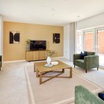 Modern living room with green sofas and TV.