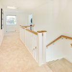 Modern carpeted hallway with wooden handrails.