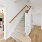 Modern hallway with staircase, wooden floor, living room entrance.