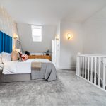 Modern attic bedroom with skylight and blue headboard.