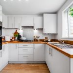 Modern kitchen with white cabinets and wooden countertops.