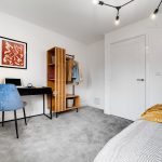 Modern bedroom with desk, chair, and clothes rack.