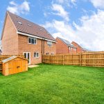 New brick house with fenced garden and shed.