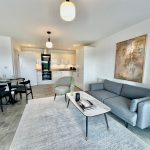 Modern living room with kitchen, sofa, and table decor.