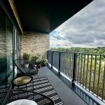 Modern balcony with seating and countryside view.