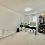 Minimalist home office with desk and bookshelf.