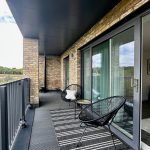 Modern balcony with chairs and glass doors.