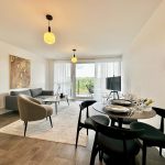 Modern living room with large windows and dining area.