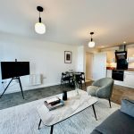 Modern open-plan living room with kitchen and TV.