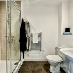 Modern bathroom with shower, sink, toilet, and towels.