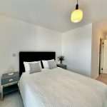 Modern minimalist bedroom with white decor and flowers.