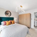 Modern bedroom with bed, lamps, wardrobe, and bathroom door.