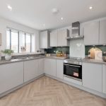 Modern kitchen with white cabinets and wooden flooring.