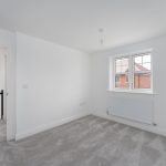 Empty carpeted room with window and radiator.
