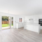 Modern kitchen with white cabinets and garden view.