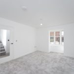 Empty white room with stairway door and window.