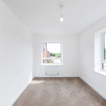 Bright empty room with windows and beige carpet.