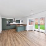 Modern kitchen with green cabinets and wooden flooring.