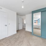 Modern bedroom with mirrored wardrobe and carpeted floor.