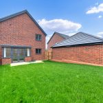 Red brick house with garden and fence.