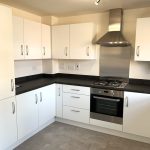 Modern kitchen with white cabinets and appliances.
