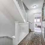 Bright hallway with carpeted stairs and ornate mirror