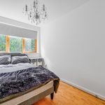 Bright bedroom with bed, chandelier, large window.