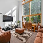 Bright living room with large window, sofas, and TV.