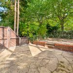 Secluded garden patio with trees and wooden fencing.