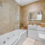 Modern bathroom with beige tiles and mirror lights.