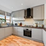 Modern kitchen with grey cabinets and wood flooring.