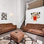 Spacious living room with brown sofas and modern art.