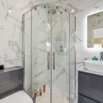 Modern bathroom with marble tiles and glass shower.