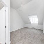 Spacious attic bedroom with grey carpet and window