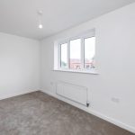 Empty white room with window and radiator.
