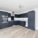 Modern kitchen with dark cabinets and wood flooring.