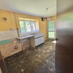 Empty kitchen with peeling paint, door ajar.