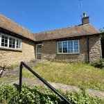 Stone cottage with bicycle and overgrown garden
